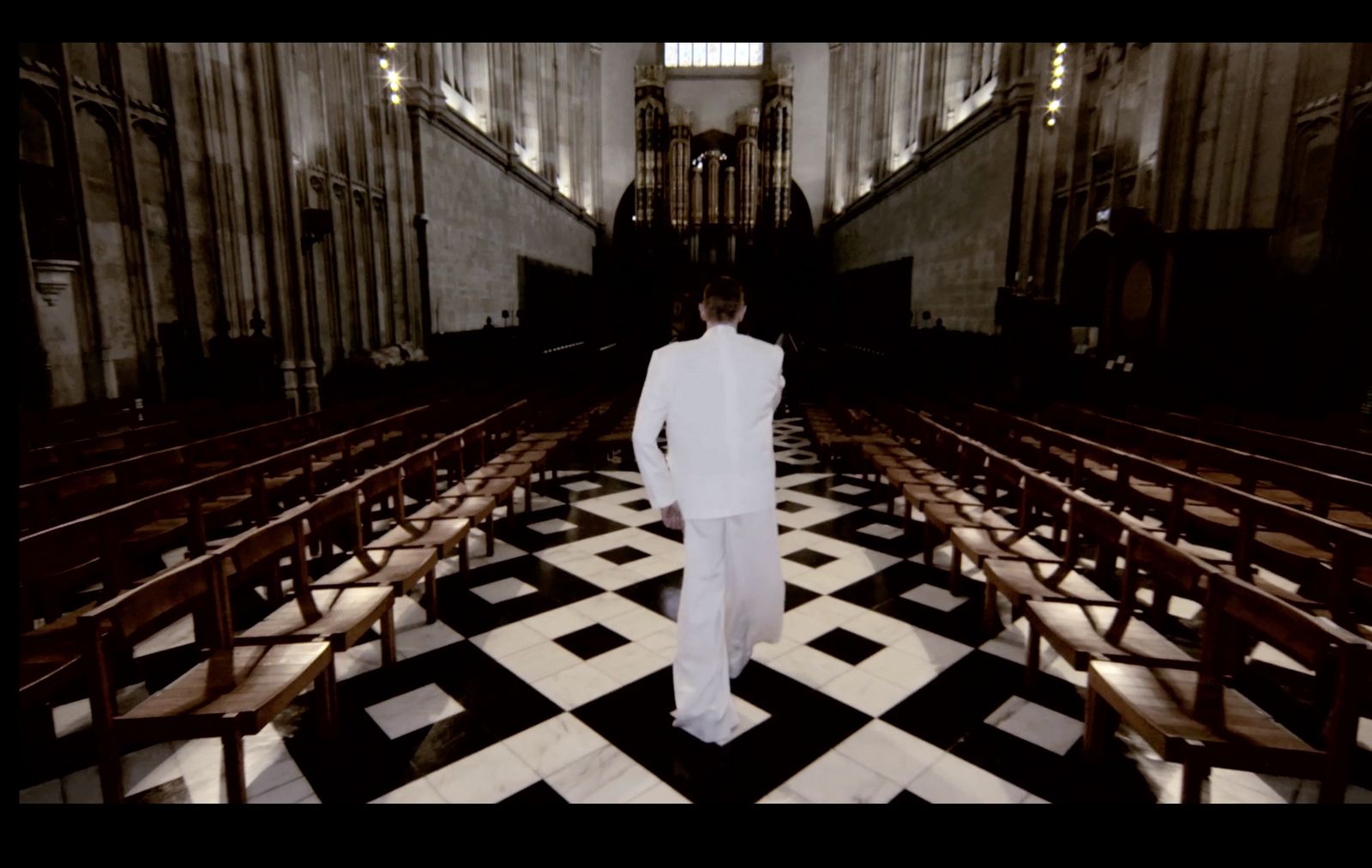 a man in a white suit standing in a church