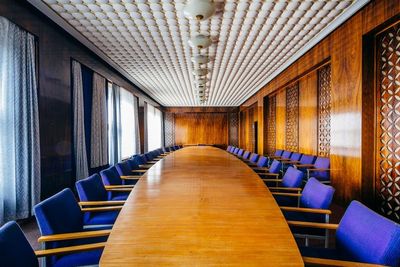 a conference room with a long wooden table and blue chairs