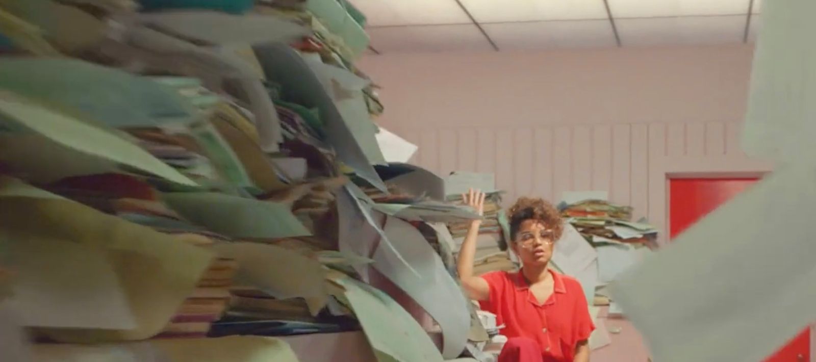 a woman standing in front of a pile of papers