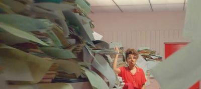 a woman standing in front of a pile of papers