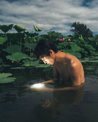 a boy in a body of water surrounded by plants