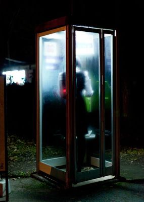 a person standing inside of a phone booth at night