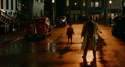 a man and a little girl walking down a street at night