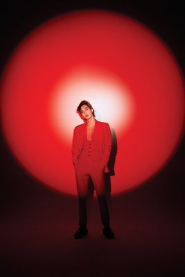 a man in a red suit standing in front of a red ball