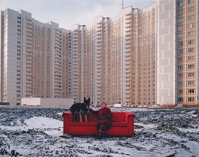 a woman sitting on a red couch with a dog