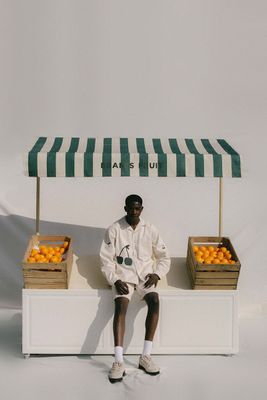 a man sitting in front of a fruit stand