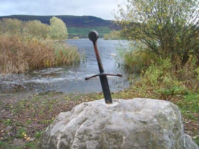 a sword sitting on top of a rock near a body of water