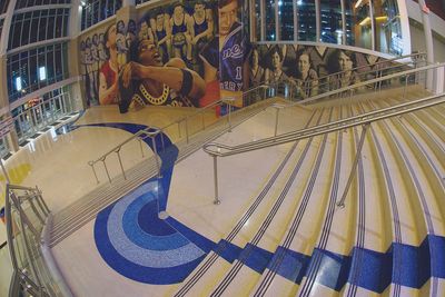 an escalator in a building with a mural on the wall