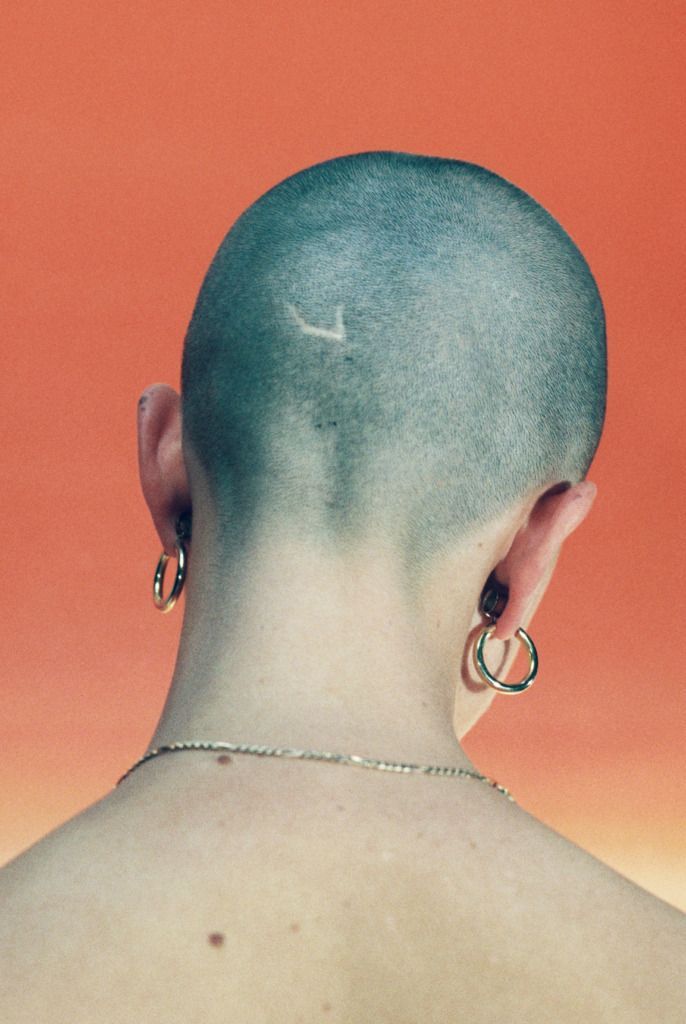 a person with a shaved head and piercings