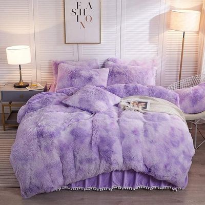 a bed with a purple comforter and pillows