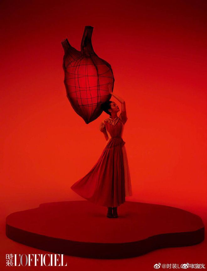 a woman in a red dress holding a heart shaped balloon