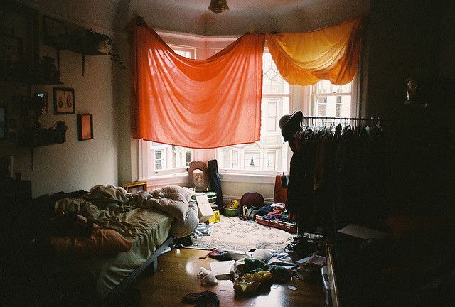 a messy room with a bed and a window