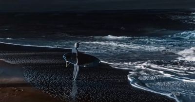 a person standing on a beach holding a surfboard