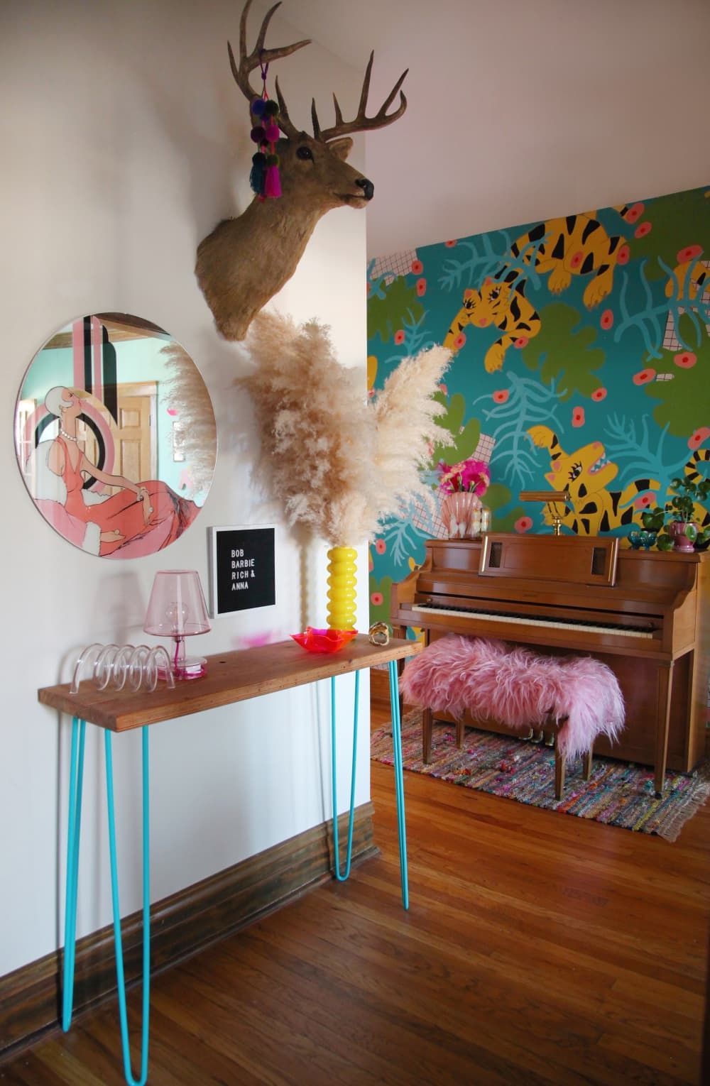 a room with a table, a piano and a deer head on the wall