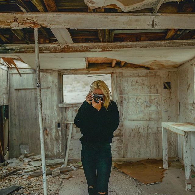 a woman taking a picture of herself in a run down house