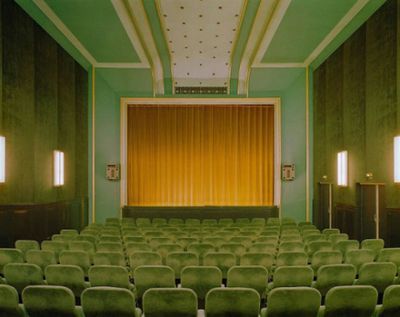 an empty auditorium with rows of green chairs