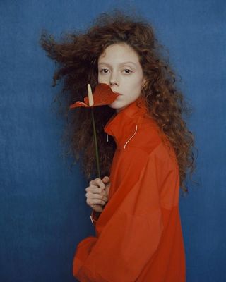 a woman with long curly hair holding a flower