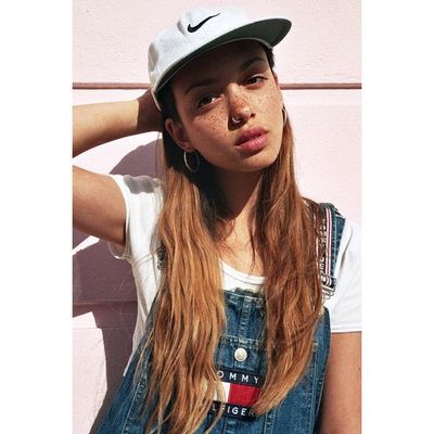 a girl with long hair wearing a hat and overalls