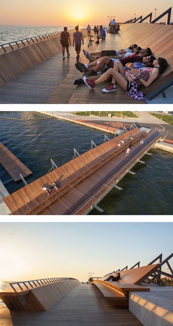 a couple of people laying on top of a wooden pier