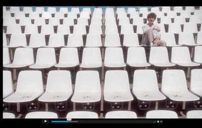 a man sitting on a white chair in a stadium