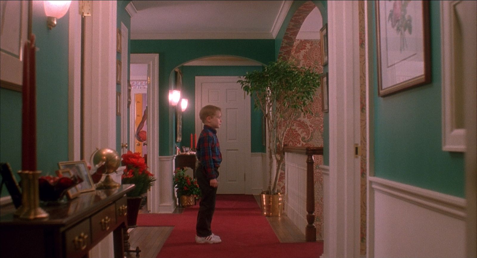 a young boy standing in a hallway in a house