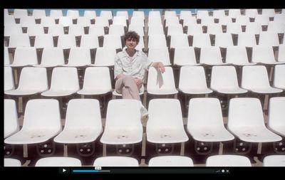 a man sitting in a row of white chairs