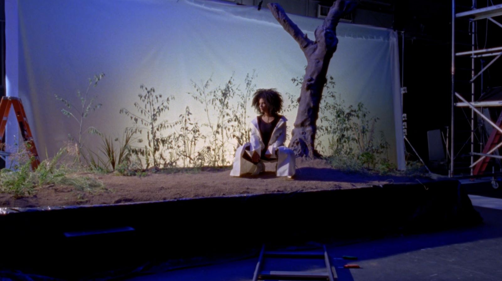 a woman sitting on a stage in front of a tree