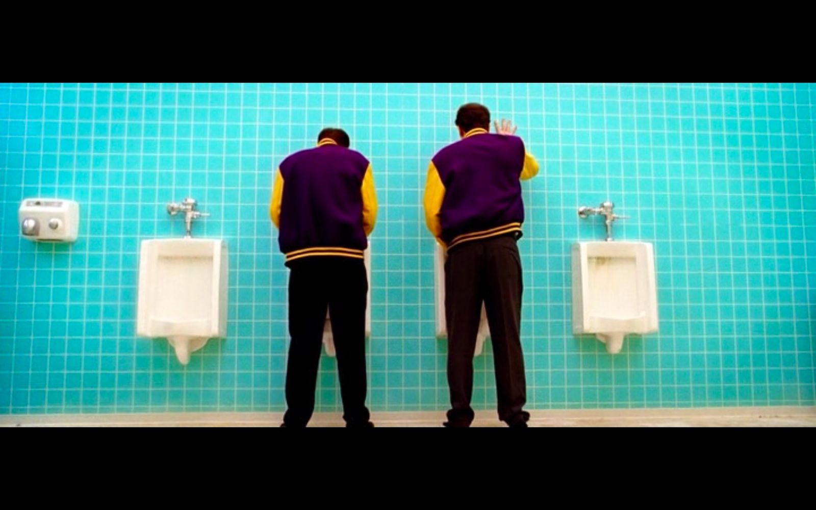 two men standing in front of urinals in a bathroom