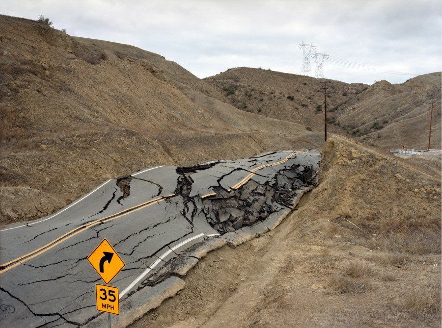 a road that has fallen over and has a sign on it