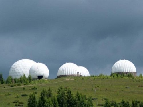 three large white domes sitting on top of a lush green hillside