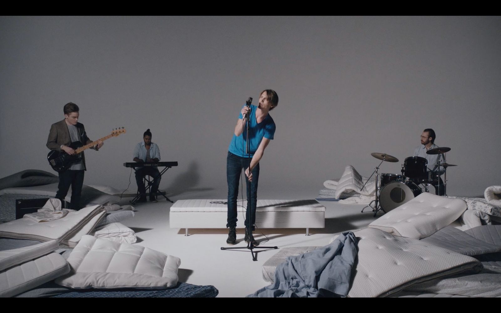 a woman singing into a microphone in a room full of mattresses