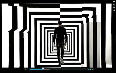 a man walking through a black and white tunnel