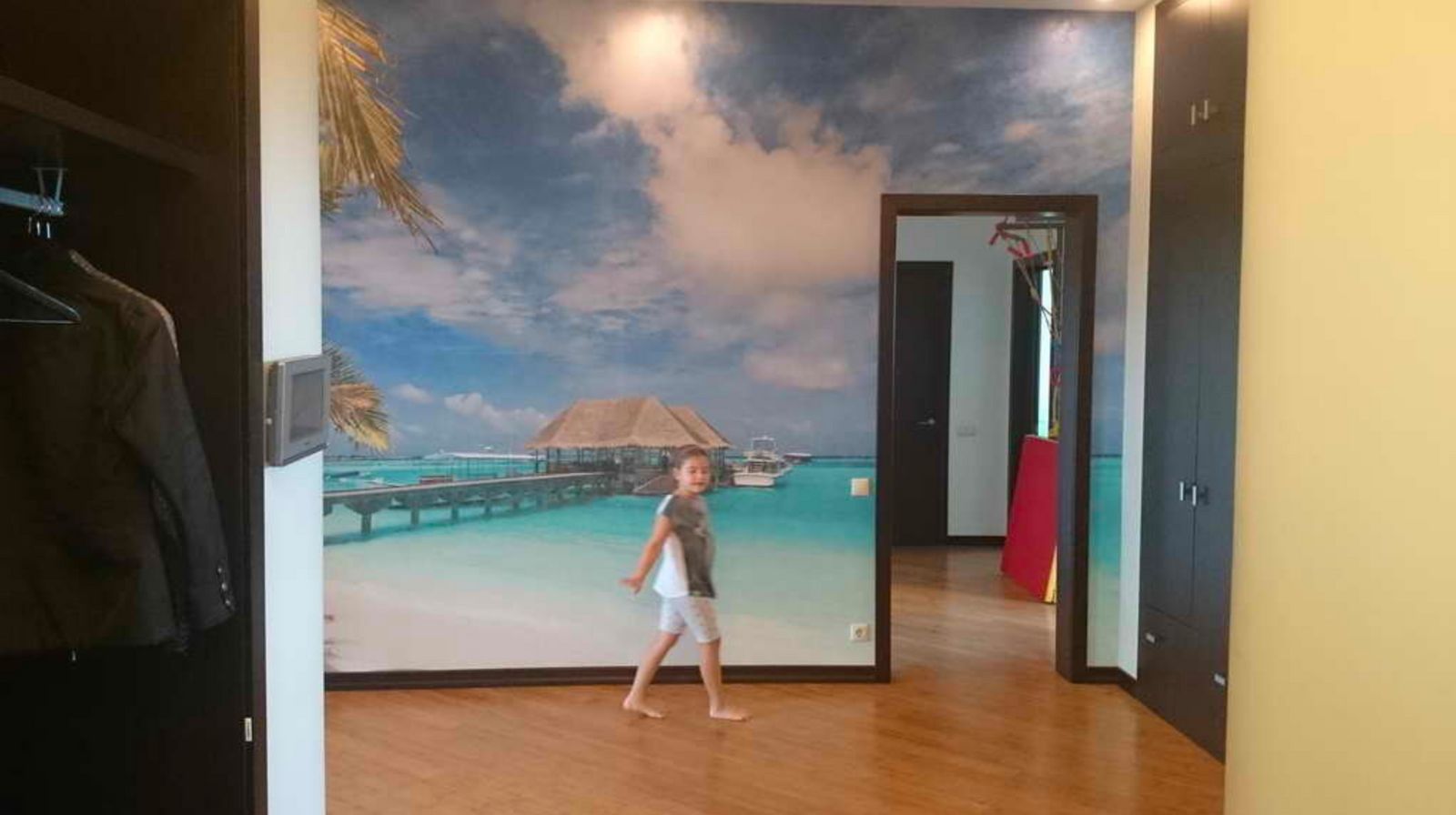 a young girl is walking through a room with a mural on the wall