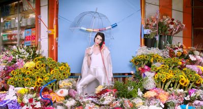 a woman standing in front of a bunch of flowers