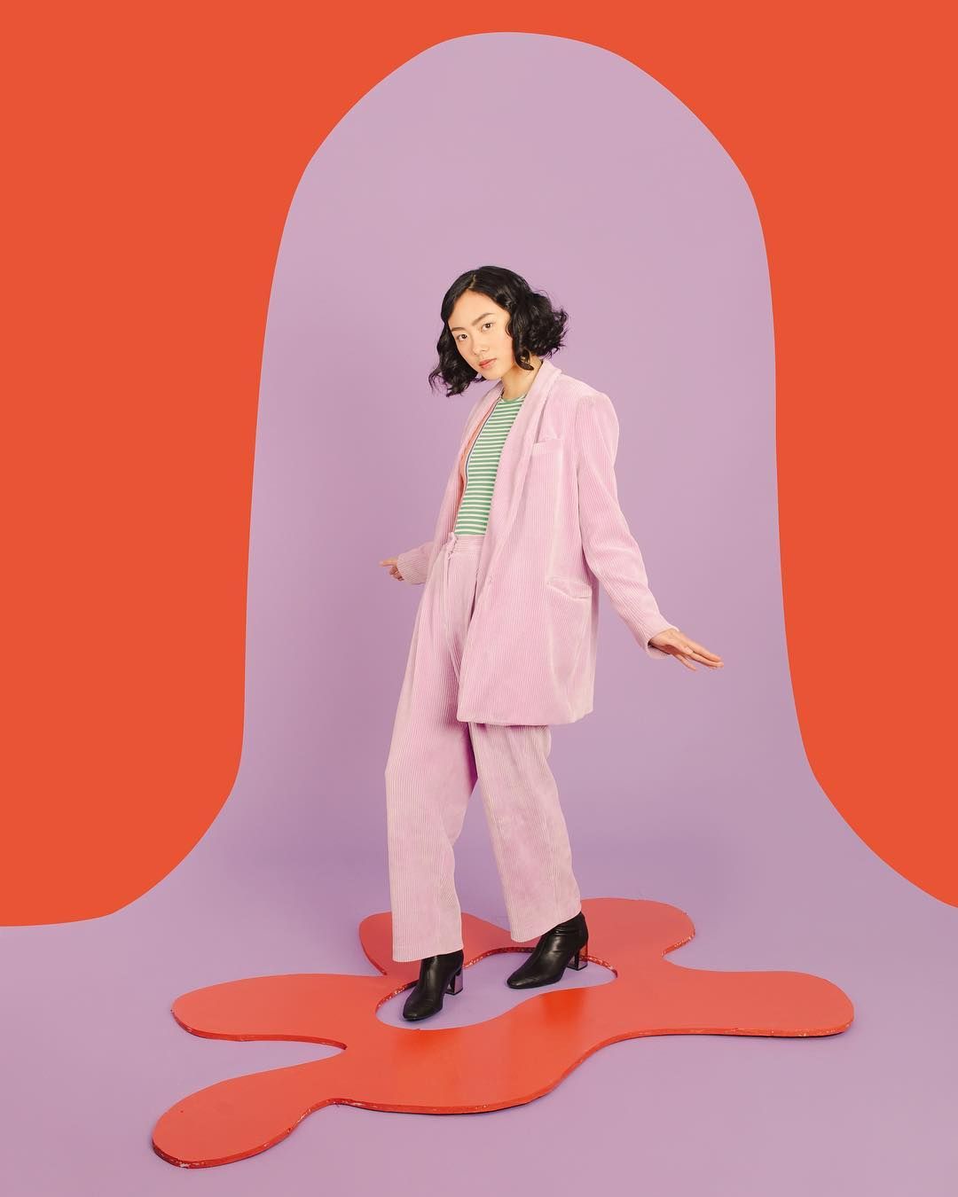 a woman in a pink suit standing in front of a purple background