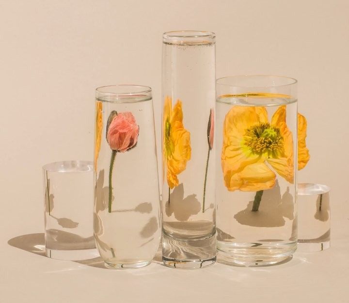 a group of three vases with flowers in them