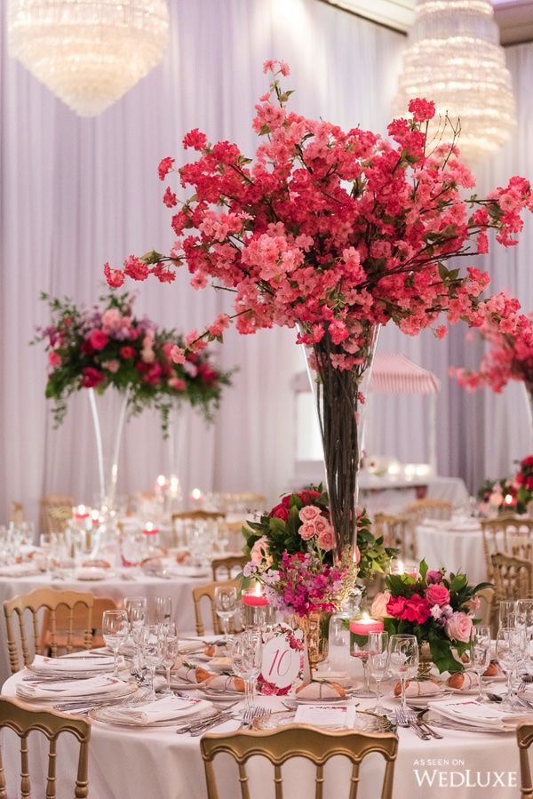 a tall vase filled with pink flowers on top of a table