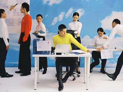 a group of people standing around a table with a laptop