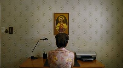 a woman sitting at a desk in front of a painting