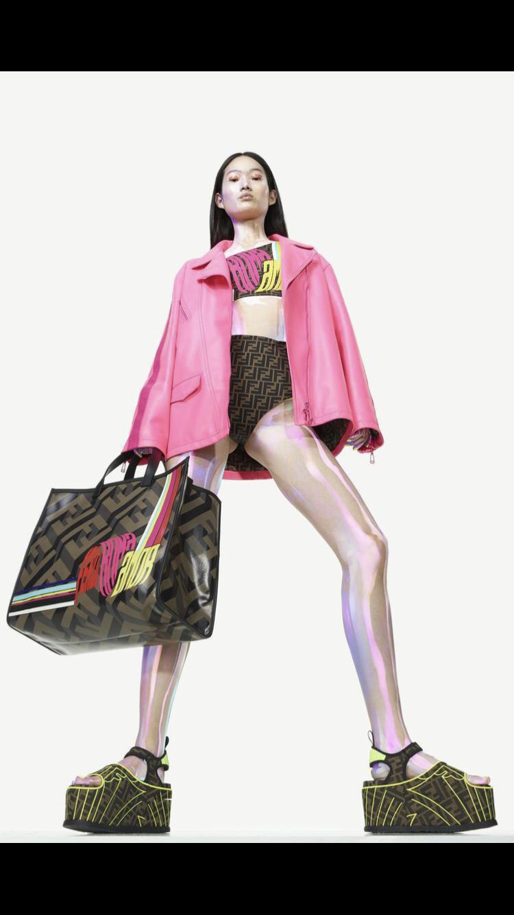 a woman in a pink coat and skirt holding a handbag