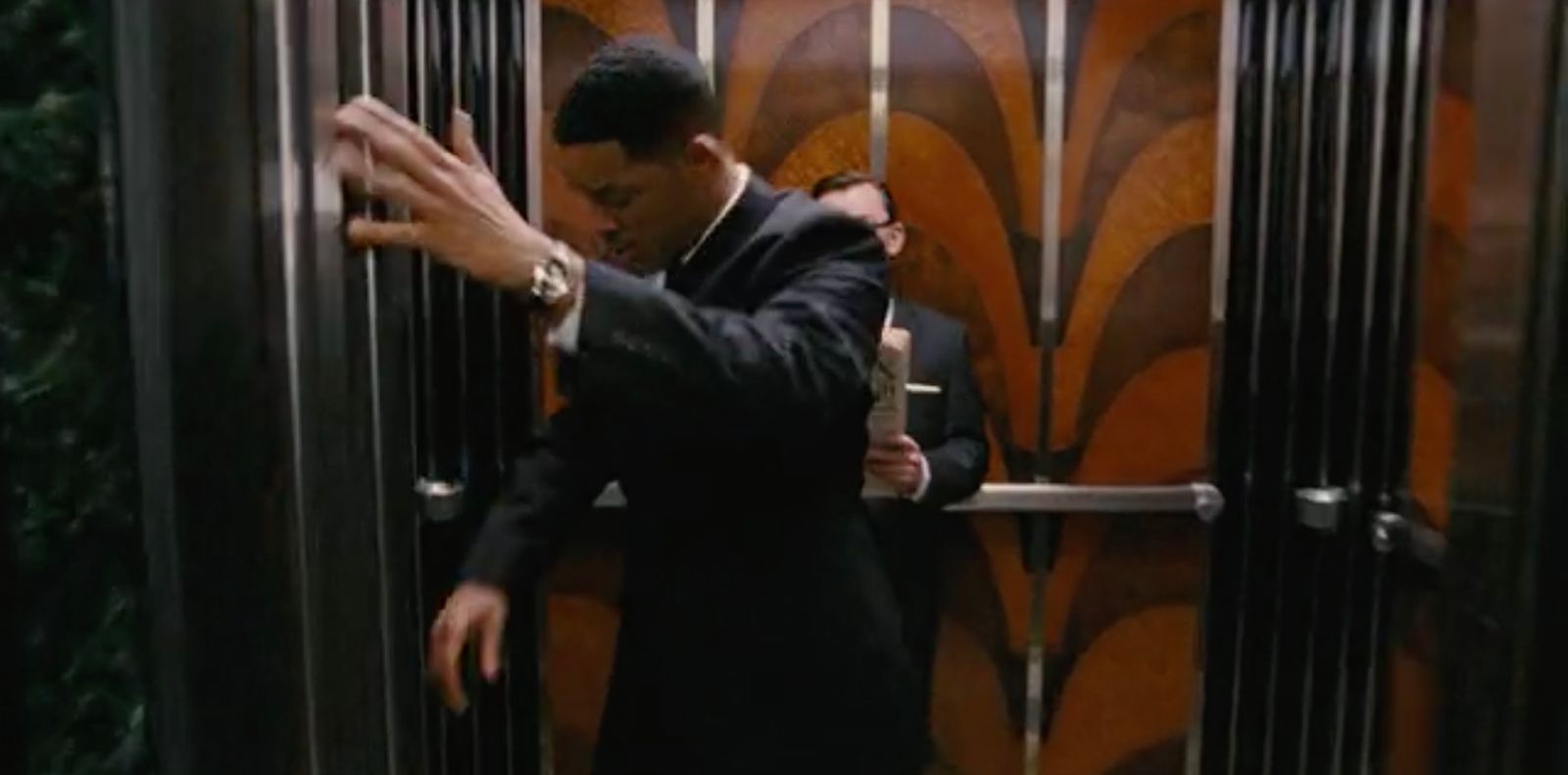 a man in a suit is entering a elevator