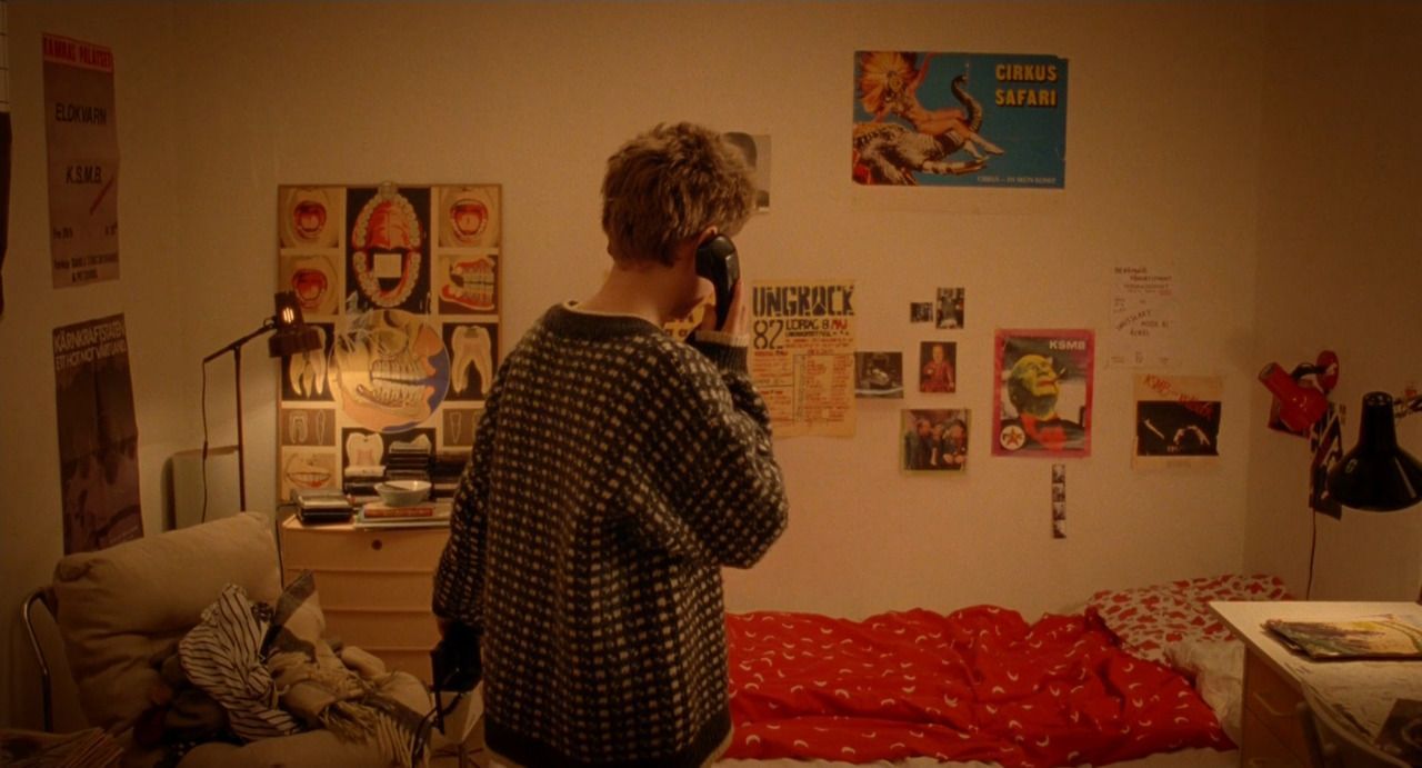 a person standing in a bedroom talking on a cell phone