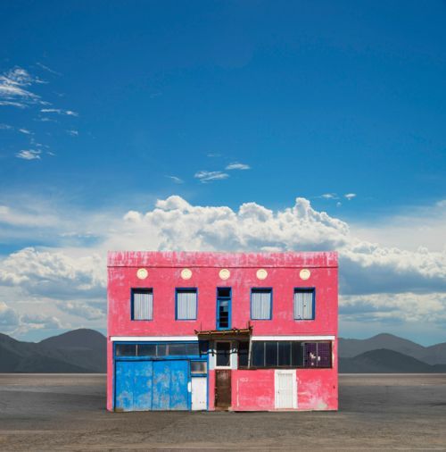 a pink building with blue doors in the middle of a desert