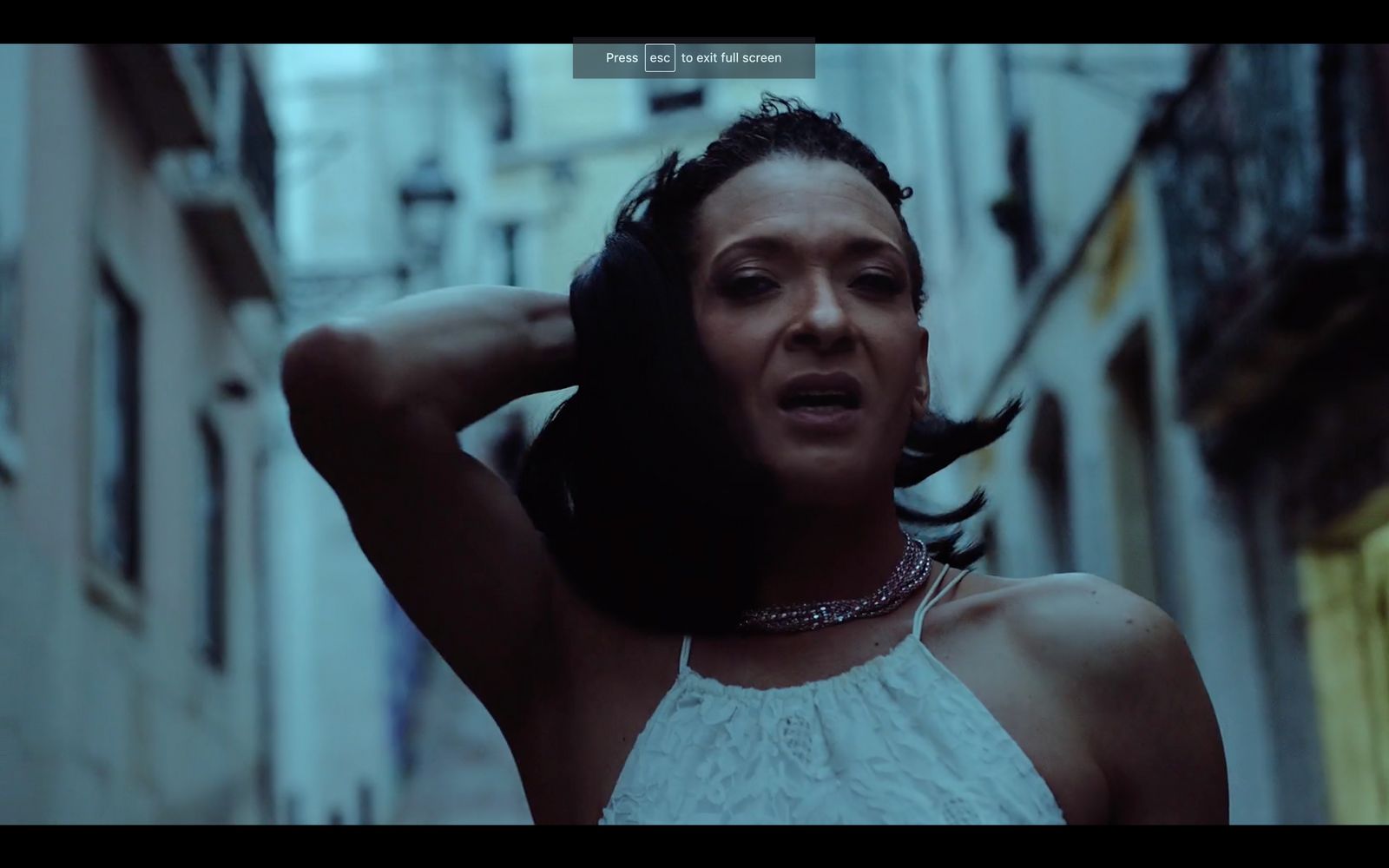 a woman in a white top standing in an alleyway