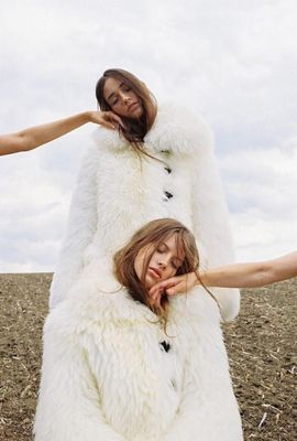 two women in white fur coats standing in a field