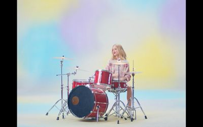 a little girl sitting on top of a drum set