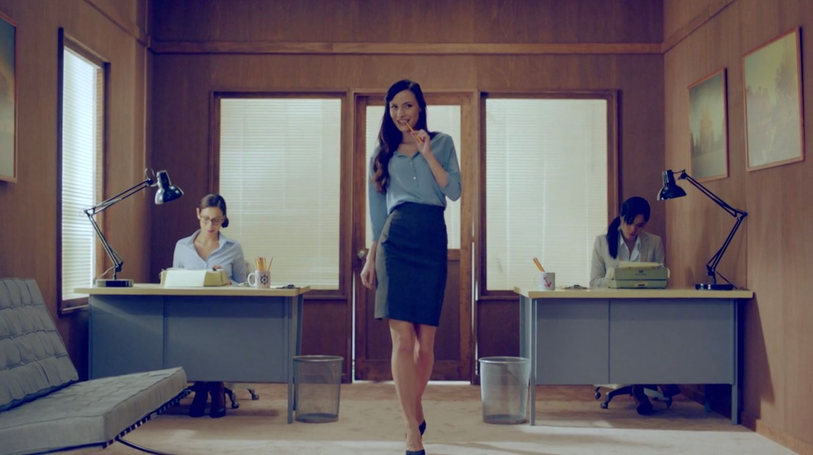 a woman in a blue shirt and skirt standing in an office