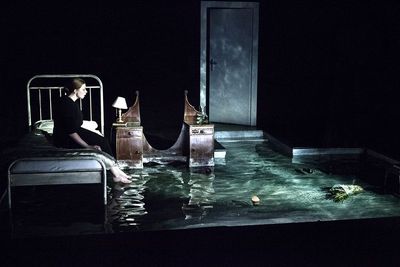 a woman sitting on a bed in a flooded room