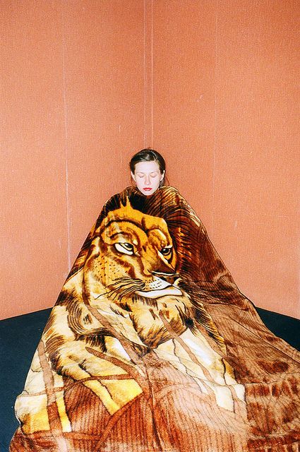 a woman sitting on top of a bed covered in a tiger blanket