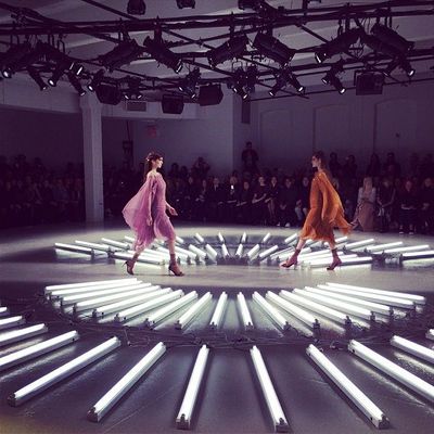 a couple of women walking across a runway